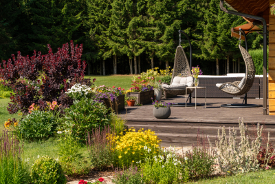 Terase ar diviem krēsliem un apkārt košas, krāsainas vasaras puķes