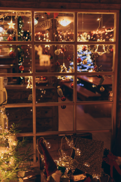 Skaisti izrotāts logs Ziemassvētku noskaņās. Ar lampiņām, sarakanām bumbiņām un egles atspulgu.